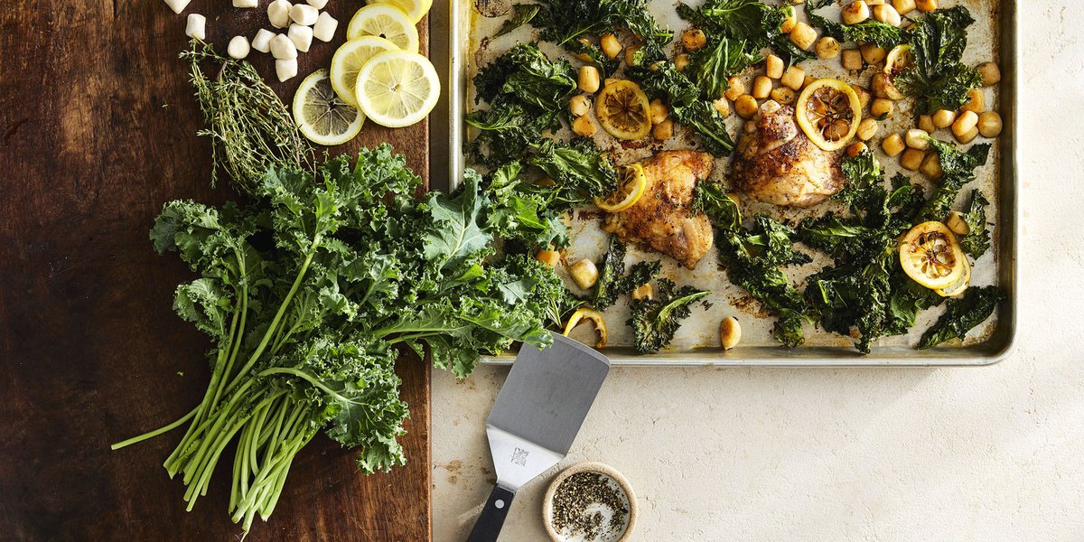 Fresh kale, gnocchi and lemon chicken thighs plated on a table with a spatula