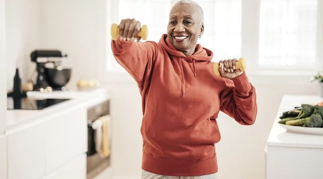 person in their kitchen holding weights doing an exercise
