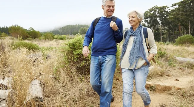 A man and a woman smiling while on a hike