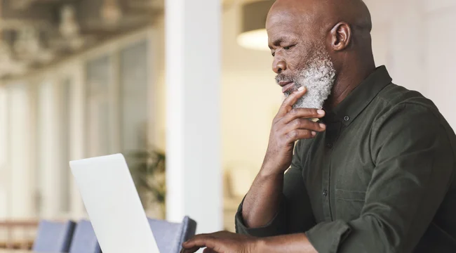 Older man in a green shirt using laptop computer at a workspace
