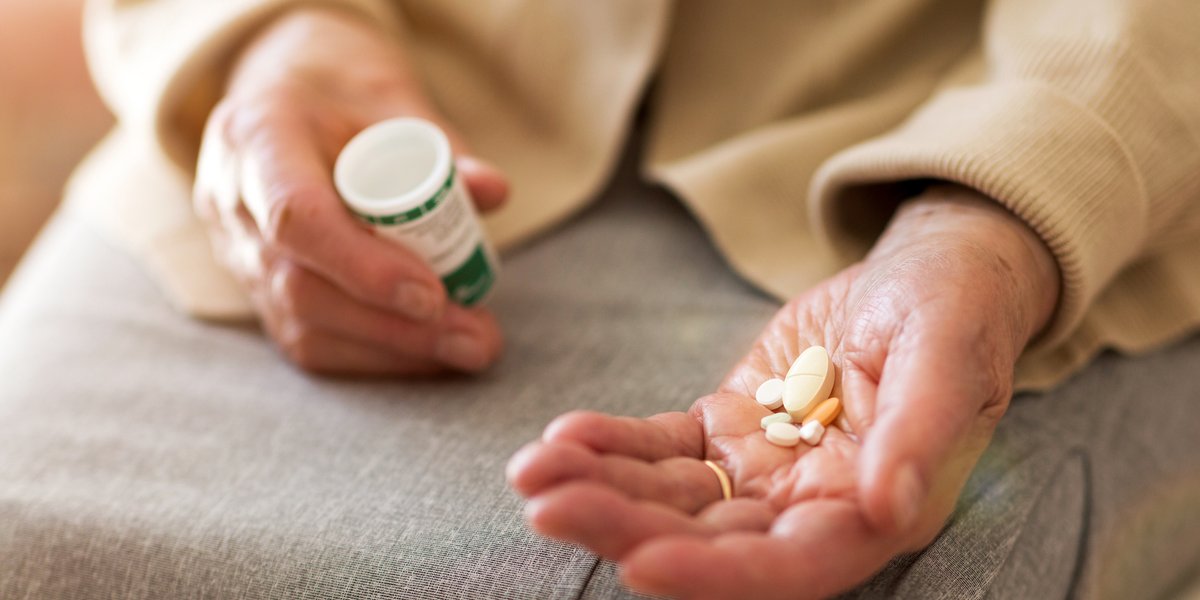 Person holding medication in one hand with the prescription bottle in the other hand